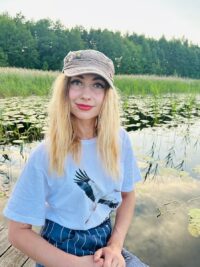 Девушка в майке с летящим белым аистом у озера