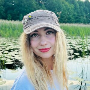 Девушка в кепке с пином большая синица на фоне озера